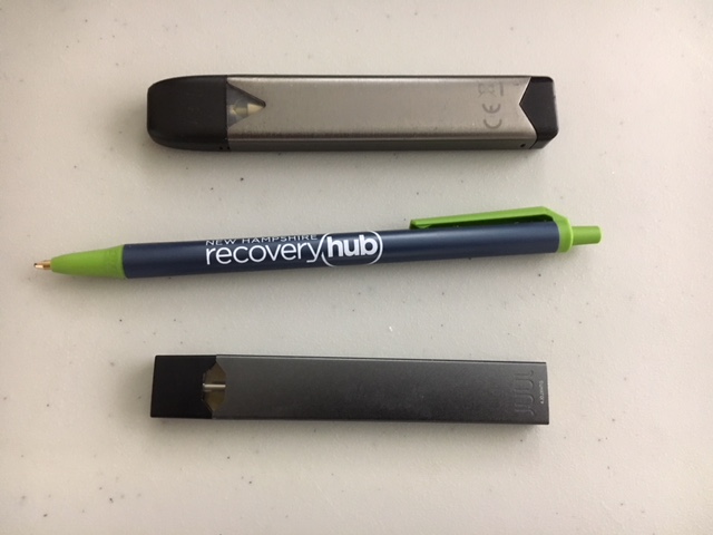A Juul e-cigarette (bottom) and a similar-looking Juno device (top), with a pen for scale.